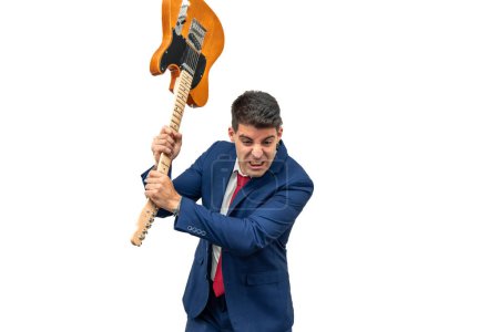 wütender Gesichtsausdruck eines Geschäftsmannes, der in einem Wutanfall eine E-Gitarre auf den Boden schlägt. verkörpert korporative Aggression und Gewalt weißen Hintergrund