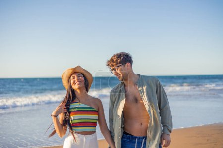Téléchargez les photos : Couple latina multiculturelle regarde affectueusement dans les yeux de l'autre tout en profitant du coucher de soleil d'été sur la plage. Leur amour est palpable au milieu des paysages côtiers sereins - en image libre de droit