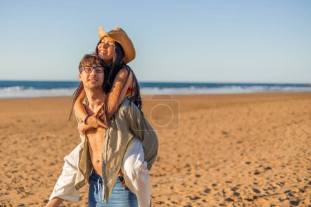 Téléchargez les photos : Copyspace multiculturel latina femme sourit affectueusement tout en étant porté sur les épaules de son petit ami à la plage par une journée d'été ensoleillée. Leurs sourires radieux reflètent la profondeur de leur amour - en image libre de droit