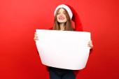 A girl in a santa hat on a red background holds an advertising poster in her hands, a banner for the sale. magic mug #619874806