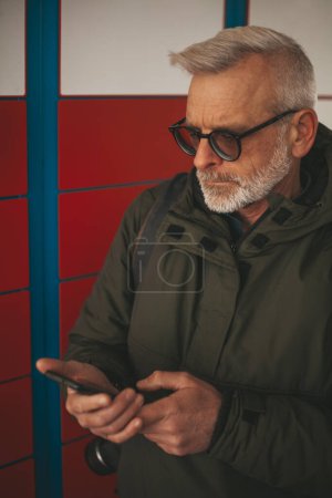 Photo for Express delivery of parcels to the post machine. Mature man takes his order. - Royalty Free Image