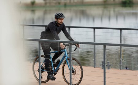 Ciclista en ropa de invierno negro en una bicicleta grevel, estilo de vida activo.