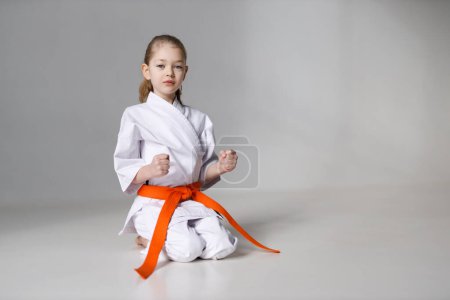Photo for Greeting little girl in karate, position of the student on a white background. - Royalty Free Image