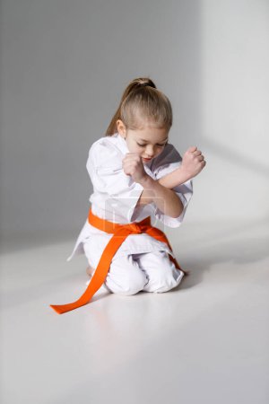 Photo for A small child is a karate student, sitting position on a white background. - Royalty Free Image
