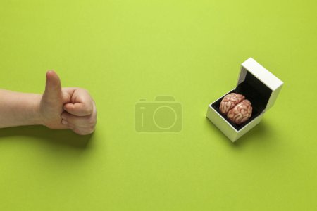 Photo for Smart human brain in box is isolated on green background as gift to dumb person. Mental development, self-improvement or problems. - Royalty Free Image