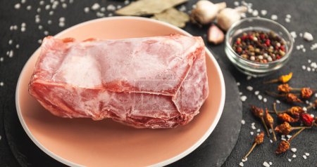 Téléchargez les photos : Morceau de viande crue congelé sur la table noire. Rime sur le produit, dégel. - en image libre de droit