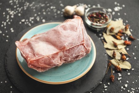 Téléchargez les photos : Morceau de viande crue congelé sur la table noire. Rime sur le produit, dégel. - en image libre de droit