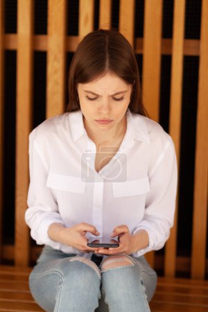 Foto de Cyberbullying. Chica molesta con un teléfono inteligente en sus manos. Acoso en Internet. - Imagen libre de derechos