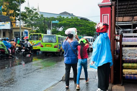 Téléchargez les photos : Ambon, Indonésie - 4 avril 2024 : Marcher sous la pluie battante - en image libre de droit