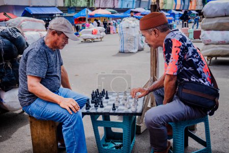 Photo for Ambon, Indonesia - April 14, 2024: People playing chess on the streets of a traditional market - Royalty Free Image