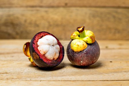Mangostanfrucht isoliert auf Holzgrund. Mangostan ist als Frucht bekannt, die einen sehr hohen Anteil an Antioxidantien enthält. Garcinia mangostana