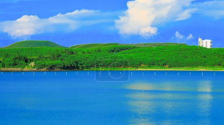 Silky sea water sight,verdant green coastal hill and blue sky, white clouds view form a dreamy scenic seascape scene. Xiyu Township Penghu County Taiwan.For branding,calender,postcard,screensave,wallpaper,poster,banner,website.High quality photo