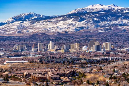 Foto de Reno, Nevada Estados Unidos - 28 de febrero de 2021: Ciudad de Reno Nevada paisaje urbano que muestra el horizonte del centro con Hoteles, Casinos y la zona residencial circundante con fondo de montaña cubierto de nieve. - Imagen libre de derechos