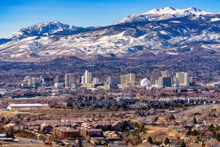 Foto de Reno, Nevada Estados Unidos - 28 de febrero de 2021: Ciudad de Reno Nevada paisaje urbano que muestra el horizonte del centro con Hoteles, Casinos y la zona residencial circundante con fondo de montaña cubierto de nieve. - Imagen libre de derechos