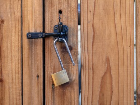 Téléchargez les photos : Lock hanging from a latch on a redwood fence. - en image libre de droit