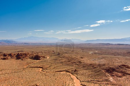 Aerial view of the arid desert southwest USA with a sand wash, red sandstone rocks and a partly cloudy blue sky with copy space.