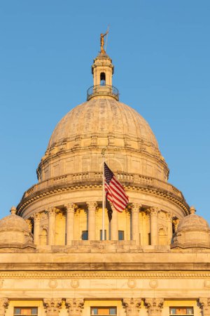 Téléchargez les photos : Drapeau américain soufflant dans le vent devant le bâtiment du Capitole de Rhode Island - en image libre de droit