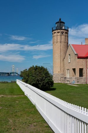 Photo for Lighthouse with a white picked fence leading to the mackinaw bridge in the distance - Royalty Free Image