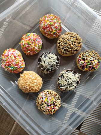 Téléchargez les photos : Mini beignets sont décorés avec des garnitures colorées, ce qui rend ce gâteau adapté comme fond. - en image libre de droit