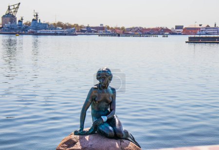 Photo for Copenhagen, Denmark - 19 april 2023. The little mermaid sits on the stone with a face mask on her hand. Symbol of Denmark. High quality photo - Royalty Free Image