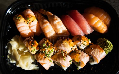 Zbliżenie bułek sushi z czerwonym kawiorem, łososiem, tuńczykiem i awokado izolowane na czarnym tle. Pyszne tradycyjne japońskie jedzenie z bułkami soshi.