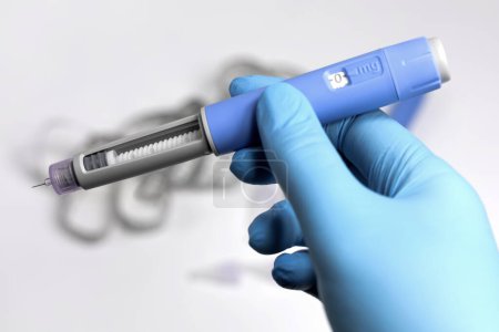 Photo for Hands in blue surgical gloves holding Ozempic Insulin injection pen for diabetics. - Royalty Free Image