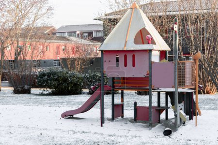 Children playground next to residential buildings in snowy winter. High quality photo