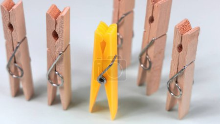 Photo for Yellow clothespin on the background of ordinary wooden clothespins. The concept of being different, gender issue, standing out from the crowd, vision of man and woman. - Royalty Free Image