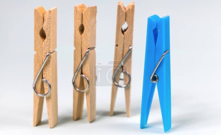 Blue clothespin on the background of ordinary wooden clothespins. The concept of being different, gender issue, standing out from the crowd, vision of man and woman.