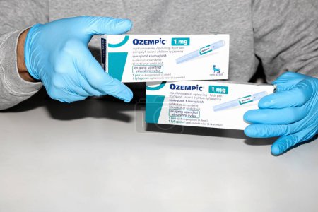Photo for Hands in blue surgical gloves holds a package with Ozempic Insulin injection pen for diabetics. Denmark - February 10, 2024 - Royalty Free Image
