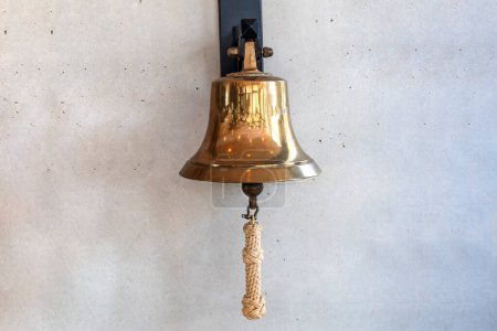 Brass bell on a gray wall indoors. High quality photo