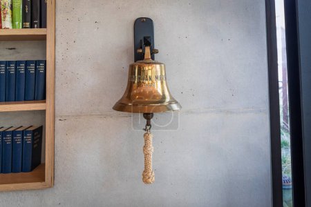 Photo for Brass bell on a gray wall indoors. Herlev, Denmark - April 4, 2024. - Royalty Free Image