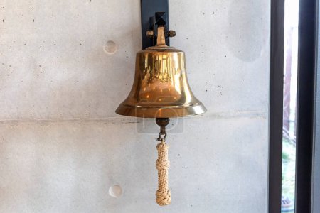 Brass bell on a gray wall indoors. High quality photo