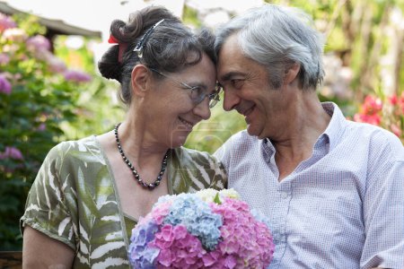 Photo for Senior Wife and Senior Man Caucasian Couple, 40+ years of True Love. Graced by Genuine Smiles in a Garden. Timeless Togetherness, Colorful Flowers, Embracing Enduring Joy - Royalty Free Image