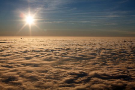 Téléchargez les photos : Soleil au-dessus des nuages dans un ciel comme la scène d'un sommet d'une montagne - en image libre de droit