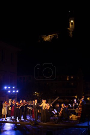 Téléchargez les photos : Ljubljana, Slovénie - 15 septembre 2021 : Concert classique ouvert au bord de la rivière Ljubljanica dans la vieille partie de la vieille Ljubljana aux heures du soir avec le château bien visible dans le ciel. - en image libre de droit