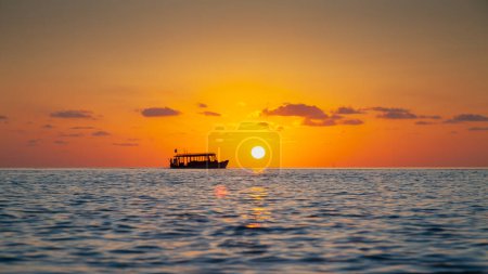 Photo for Tourist Boat on Horizon Line Close to the Sun at Sunset in The Maldives - Royalty Free Image