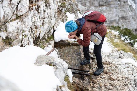 Caminante de agua potable con las manos de una fuente de agua de alta montaña en una caminata en los Alpes europeos