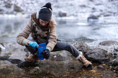 Foto de Contaminación ambiental Experiencia femenina Tomando una muestra de algas de un lago alpino en invierno - Imagen libre de derechos