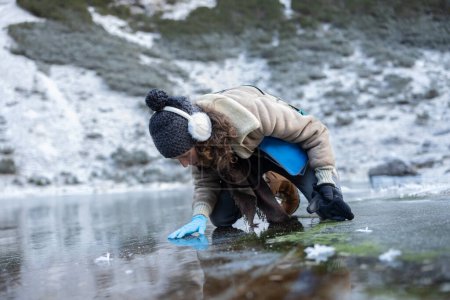 Foto de Experiencia en biología de mujeres adultas que comprueban el medio ambiente de los lagos congelados en las altas montañas de los Alpes europeos - Imagen libre de derechos
