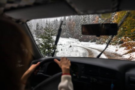 Téléchargez les photos : Une conductrice qualifiée s'attaque à des routes glissantes et glacées dans une chute de neige, manœuvrant dans des conditions météorologiques imprévisibles - en image libre de droit