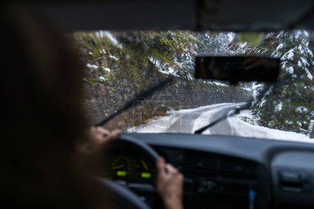 Téléchargez les photos : Une conductrice confiante affronte les routes hivernales impitoyables, navigue habilement sur les surfaces glissantes et les changements météorologiques - en image libre de droit