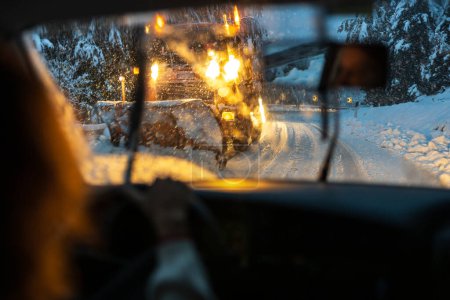 Téléchargez les photos : Routes d'hiver dangereuses : vue de l'intérieur d'une voiture en Europe, conduite sur une route enneigée dans des conditions de lumière et de visibilité difficiles - en image libre de droit