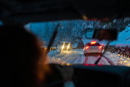 Téléchargez les photos : Au-dessus de l'épaule Vue d'un conducteur confiant faisant face aux défis des routes enneigées, des surfaces glacées et des changements météorologiques le matin - en image libre de droit