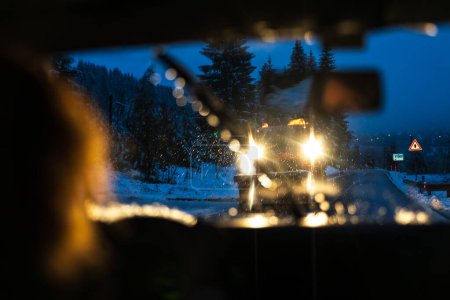Téléchargez les photos : Maîtrise de la route hivernale : vue au-dessus de l'épaule d'une conductrice compétente qui gère habilement des routes glissantes et glacées et des changements de temps soudains le matin pour se rendre au travail - en image libre de droit