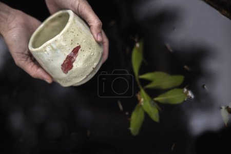 Young Woman Artisan Showing Ceramic Unique Design Cup over zen Pond Set Up