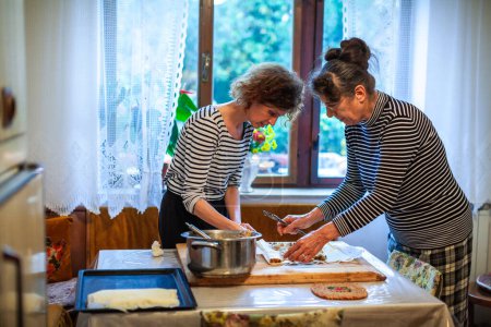 Photo for Senior and Mature Women Preparing Apple Strudel in the Domestic Kitchen - Royalty Free Image