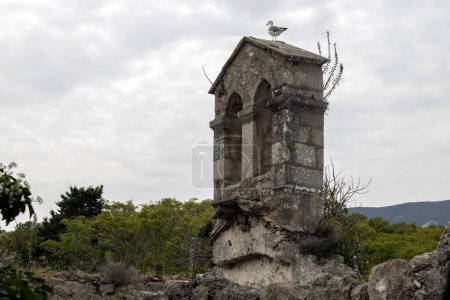 Foto de Gaviota Sentado en la cima de la Campana Costa de Ruinas del antiguo Monasterio de San Martín de los Ángeles en la ciudad croata de Osor, Isla de Cres - Imagen libre de derechos