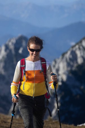 Foto de Senderista mujer adulta serena Fast Step Cardio Ascent en la cima de una montaña en los Alpes europeos - Imagen libre de derechos