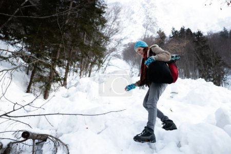 Photo for Careful descend from Snowy Mountain in Dangerous Icy Conditions by a Woman Hiker Equipped with Hiking Boots and Snow Cleats from Low Perspective. - Royalty Free Image